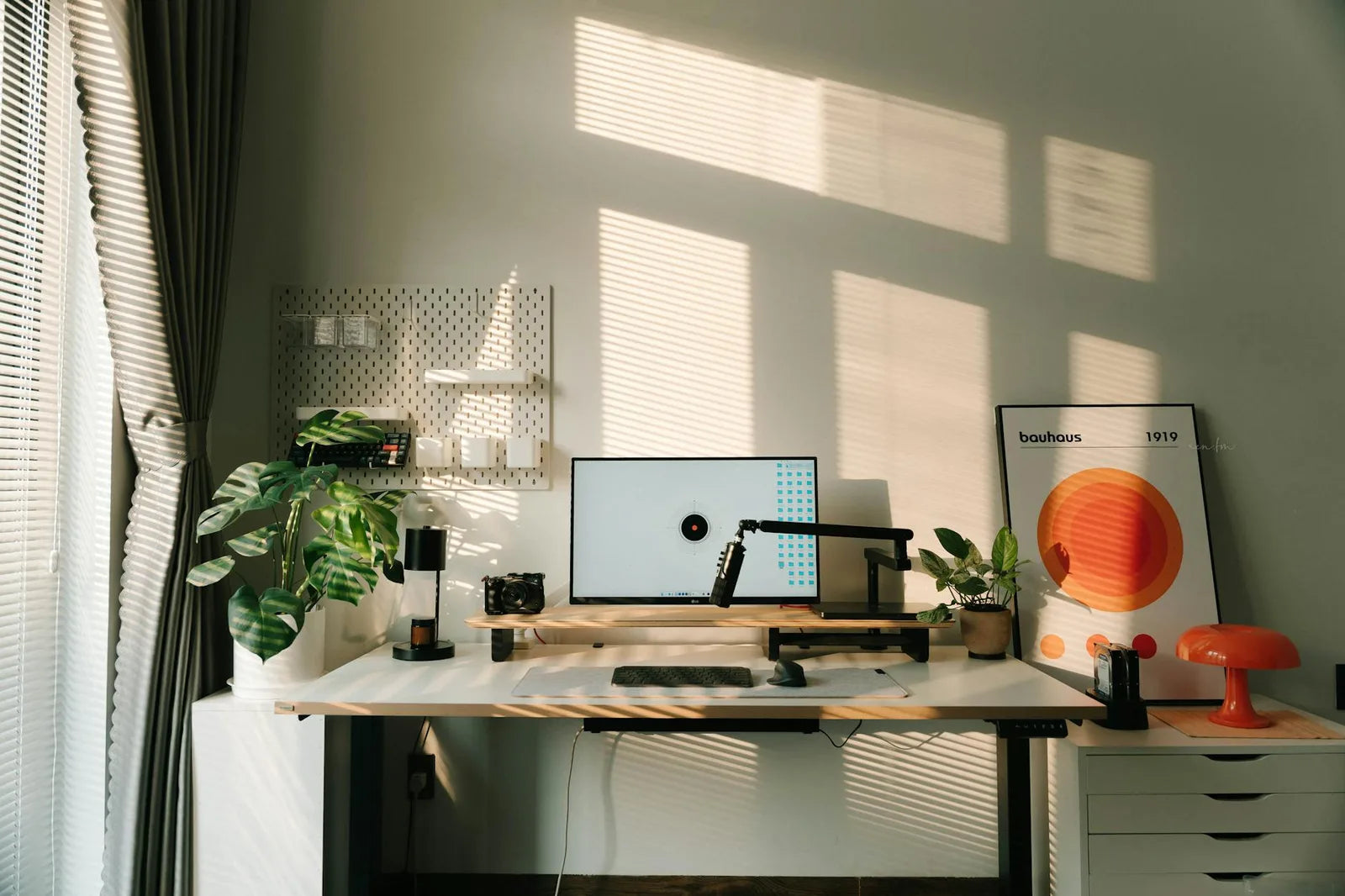 Home office with a Bauhaus poster on the wall, desk lamp, plant