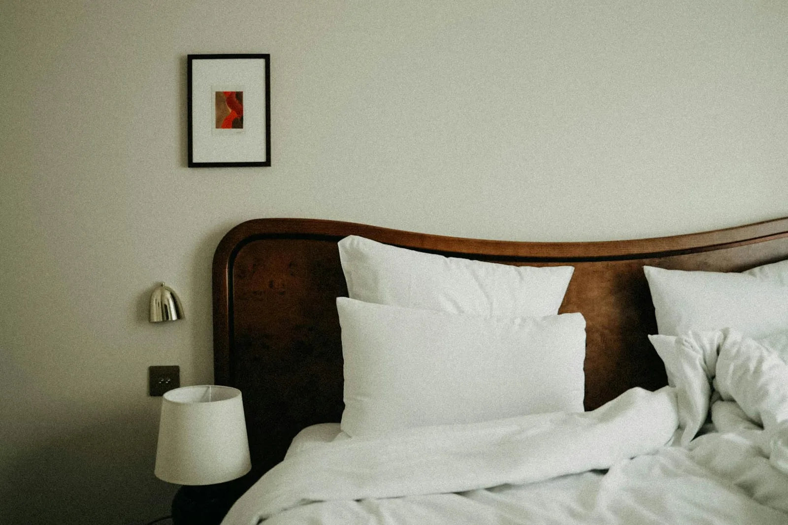 Bedroom with poster above the bed, white sheets, natural light