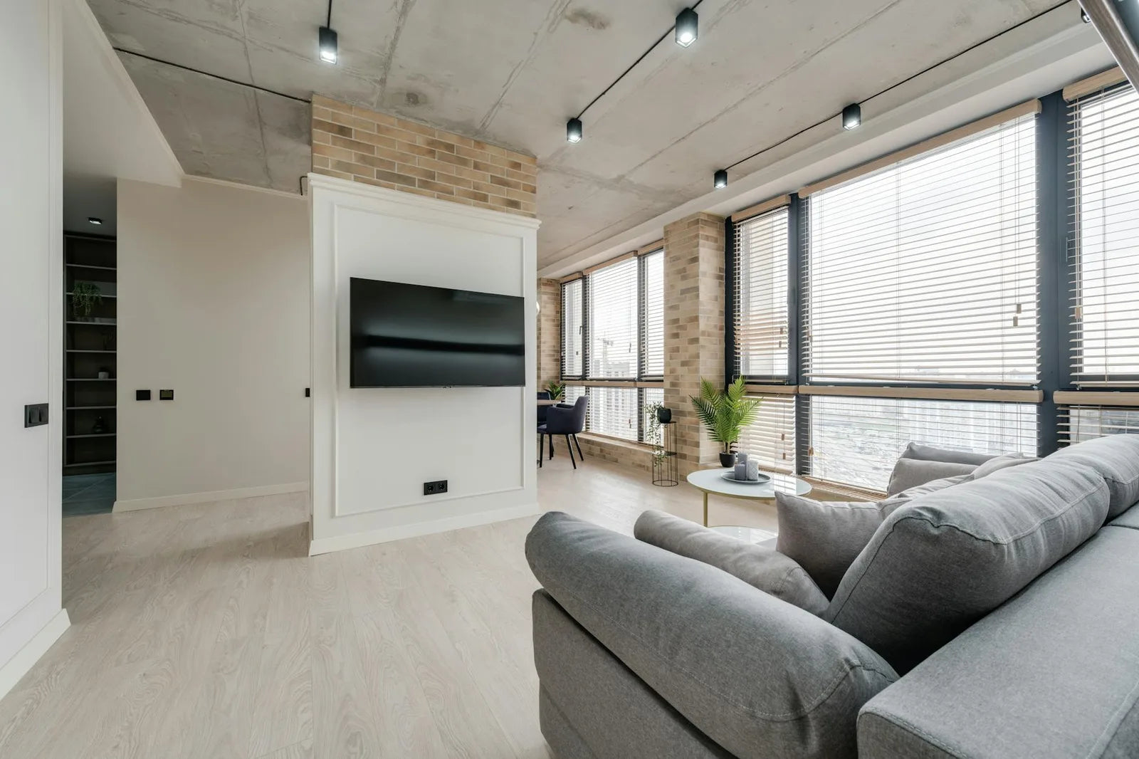 Bright living room with large bay windows, grey sofa, framed posters