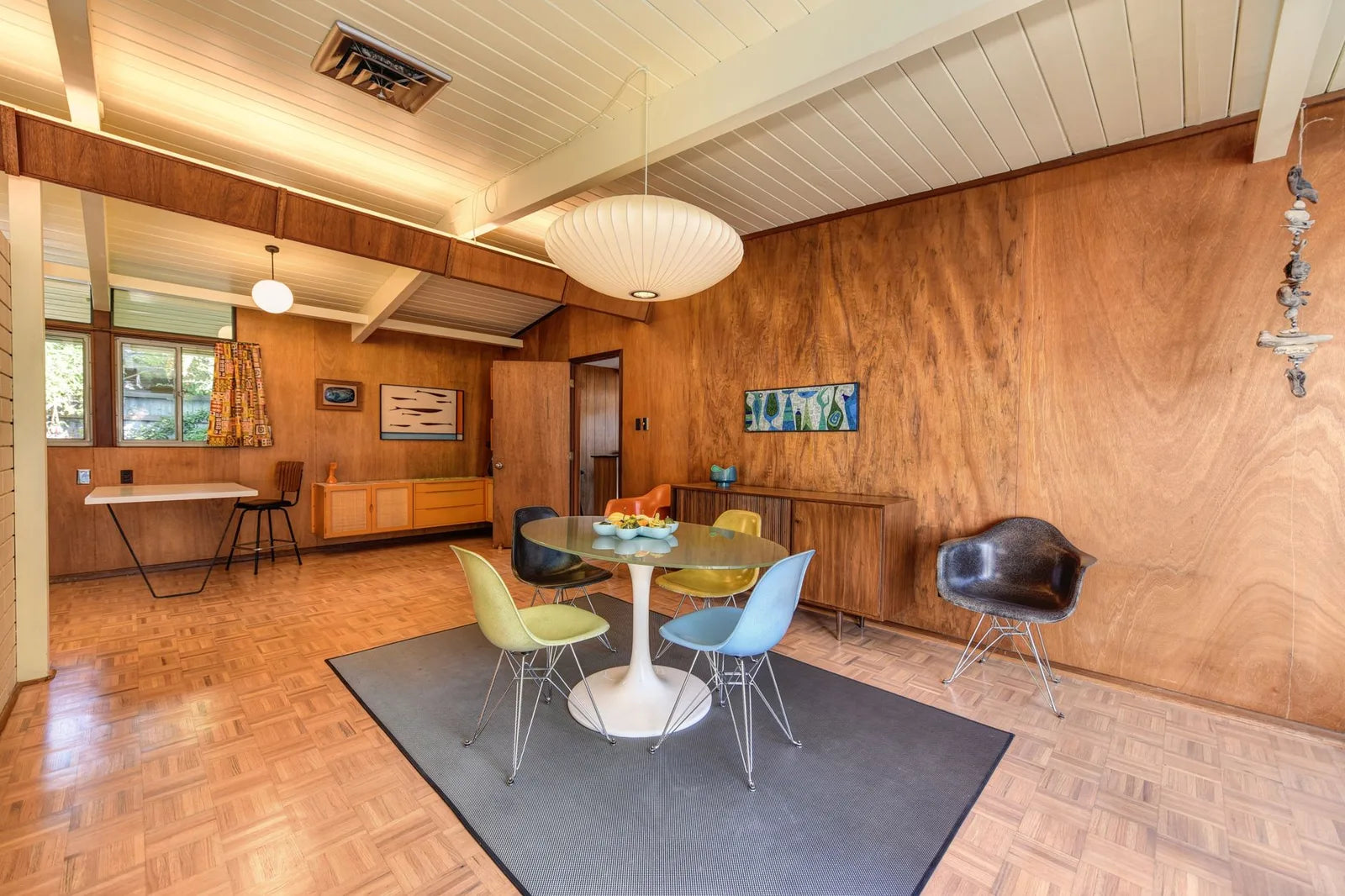 Mid-century living room with tulip chair, light parquet, abstract poster